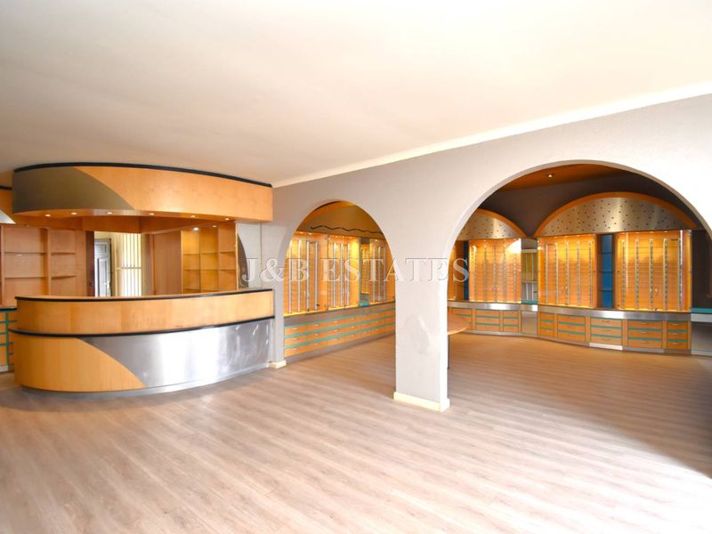 Spacious retail interior featuring custom built-in wooden cabinetry, display shelving, a curved service counter, and elegant arched architectural details.
