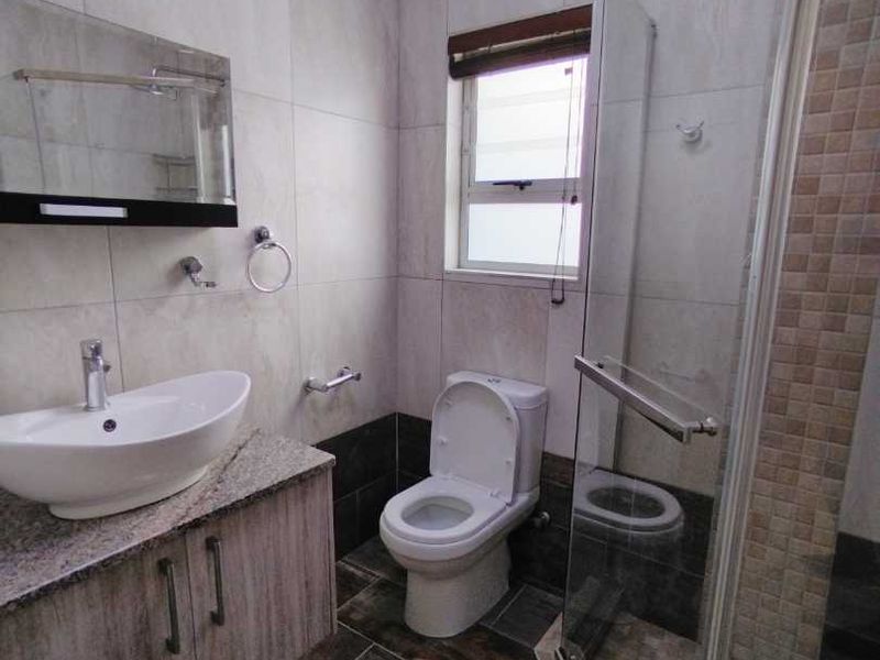 Modern bathroom featuring a vessel sink on a granite-topped vanity, a glass-enclosed shower, and contemporary floor-to-ceiling wall tiles.