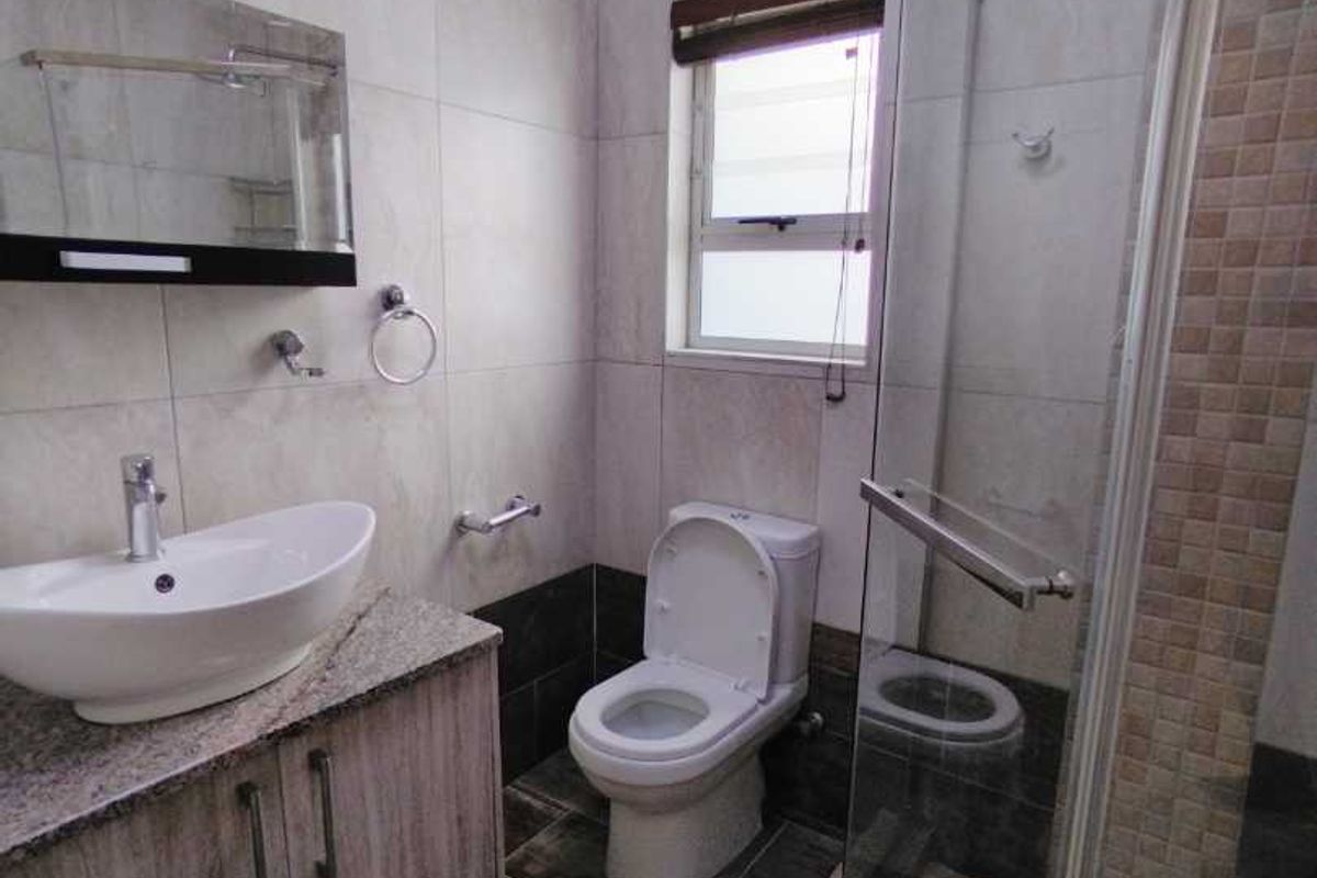 Modern bathroom featuring a vessel sink on a granite-topped vanity, a glass-enclosed shower, and contemporary floor-to-ceiling wall tiles.