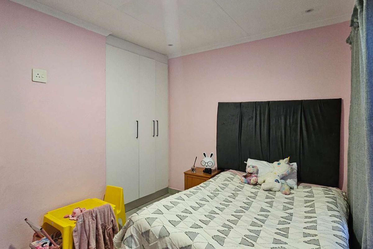 A bedroom featuring built-in wardrobes, recessed ceiling lighting, and coving, finished with pink wall paint.