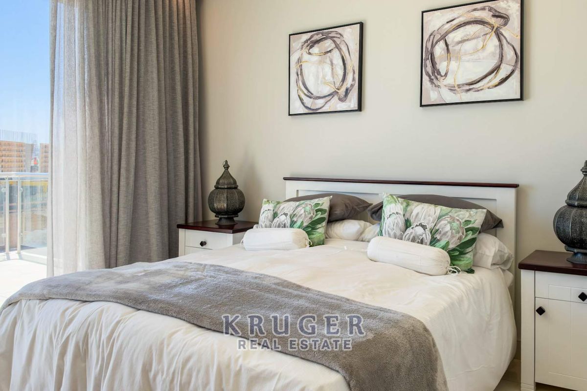 A well-maintained bedroom featuring tiled flooring and direct access to a private balcony through large sliding glass doors.