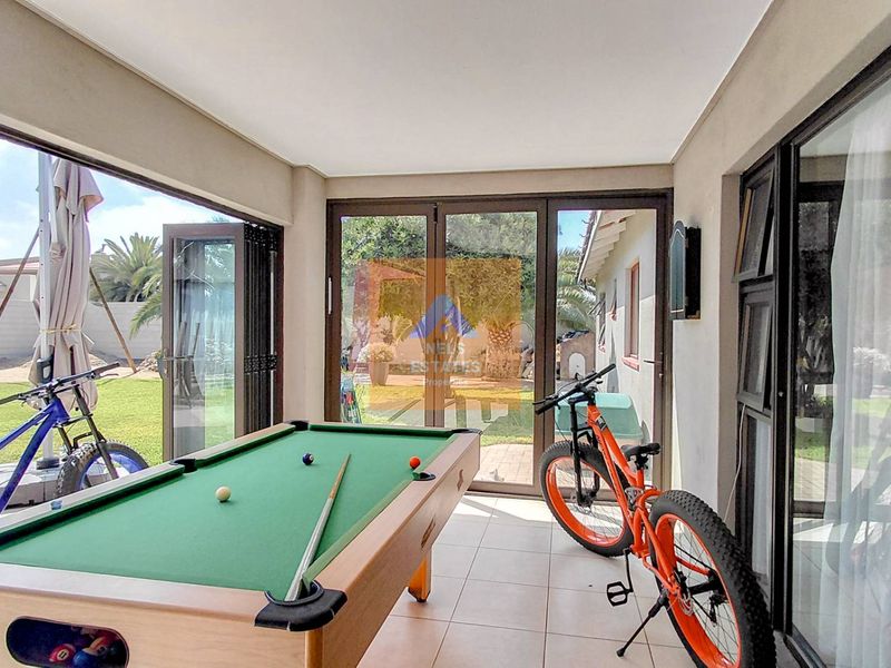A bright, enclosed patio area featuring large aluminium stackable doors that provide seamless access to the garden.