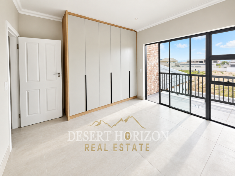 A bright, modern bedroom featuring built-in cupboards, large format floor tiles, and a sliding glass door leading to a private balcony.