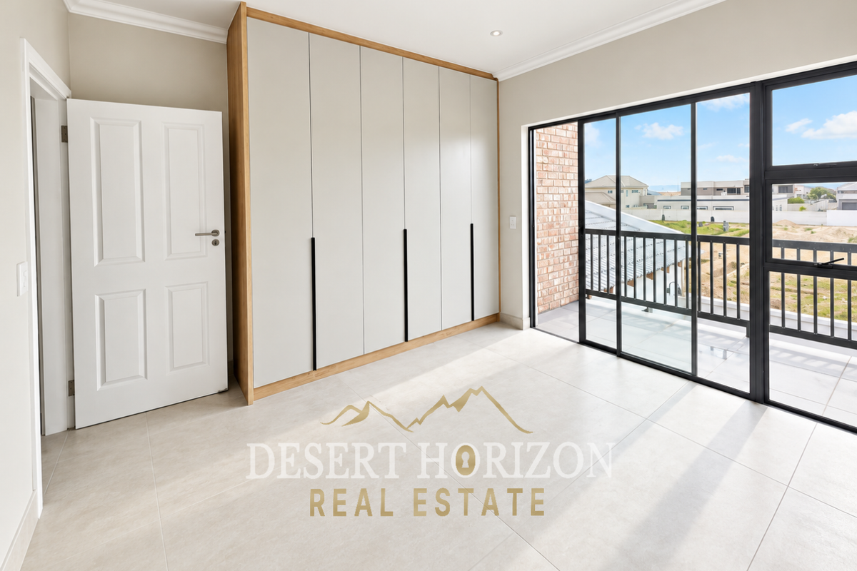 A bright, modern bedroom featuring built-in cupboards, large format floor tiles, and a sliding glass door leading to a private balcony.