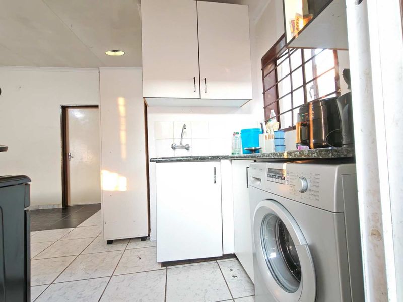 A functional laundry area featuring built-in cabinetry, a sink, and tiled flooring, providing a dedicated space for household utility and washing tasks.