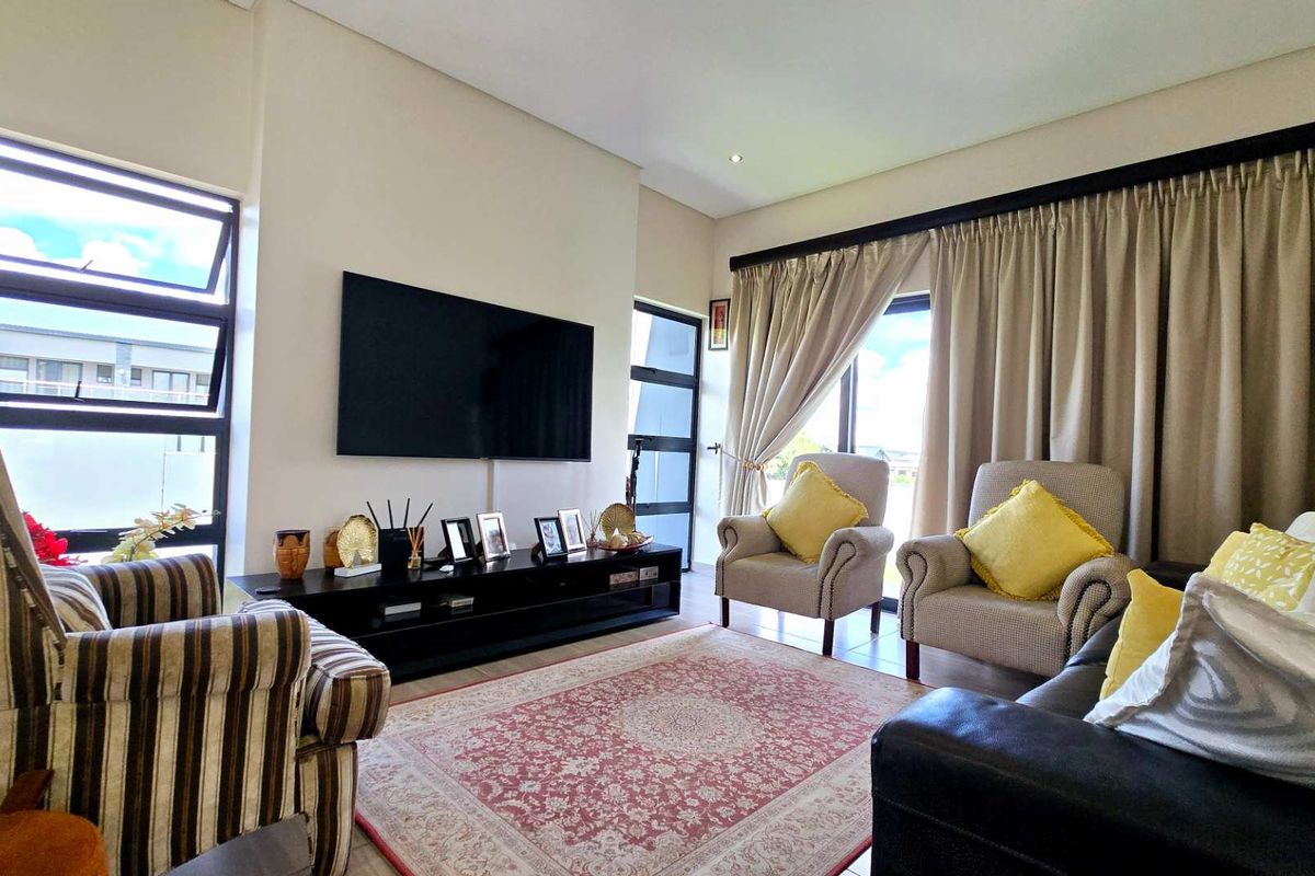 A comfortable living room featuring large windows, neutral wall finishes, and direct access to outdoor space through sliding doors.