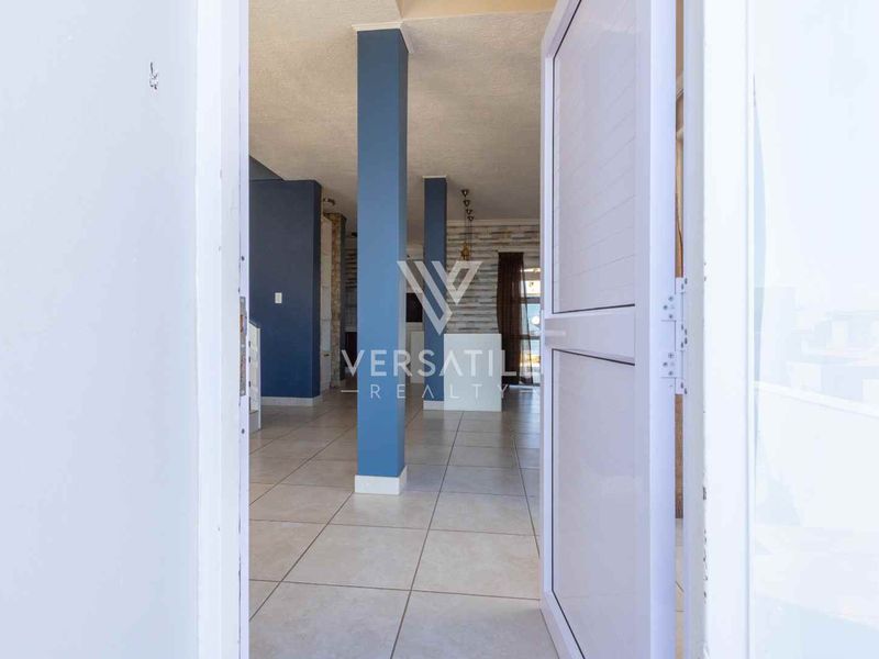An open-plan entrance area featuring tiled flooring, structural columns, and a stone feature wall, leading into the main living space.