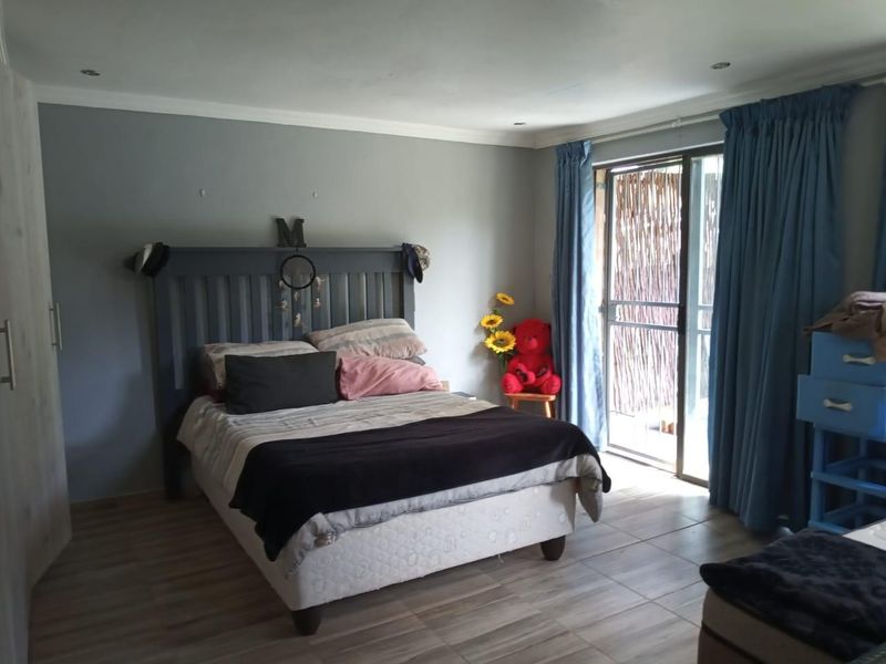 A bedroom featuring tiled flooring, recessed downlights, and a sliding glass door providing access to an outdoor area.