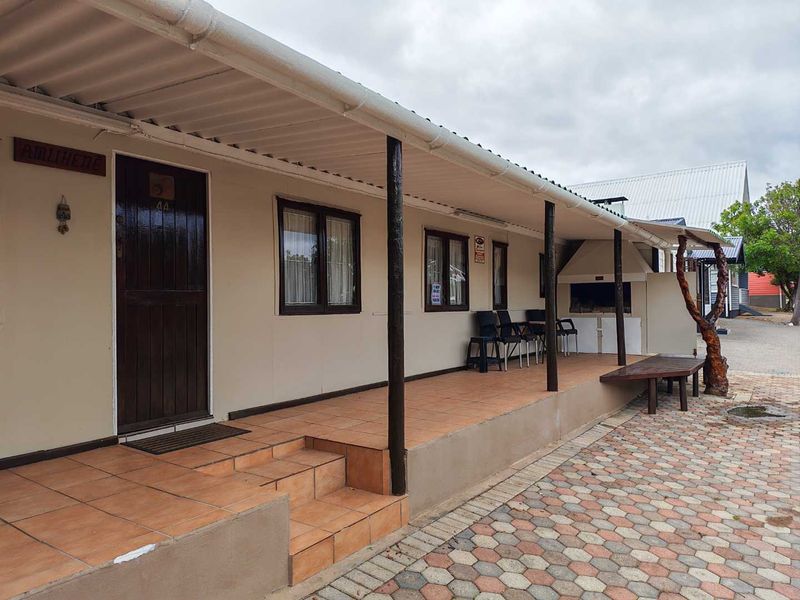 A covered patio area featuring tiled flooring, timber support posts, and a built-in braai, providing a functional outdoor entertainment space.