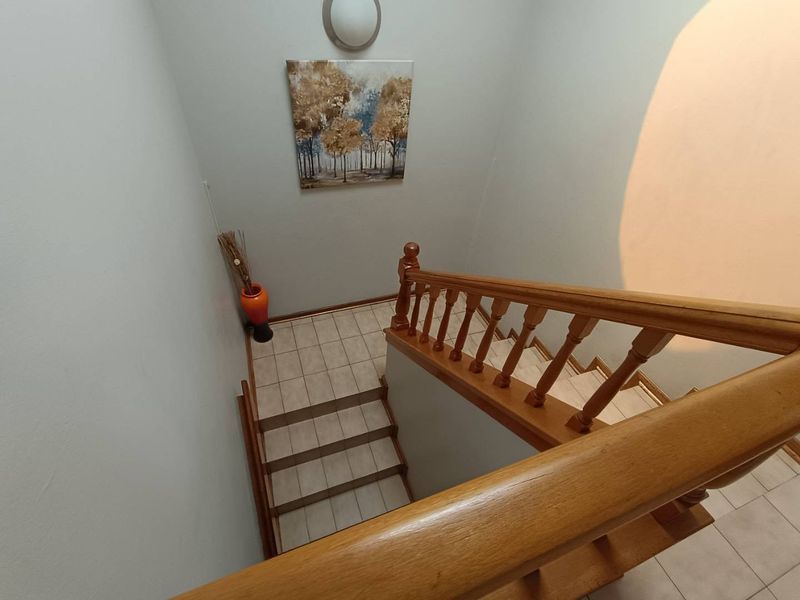 A staircase area featuring a wooden balustrade and tiled steps, providing access between levels in the townhouse.