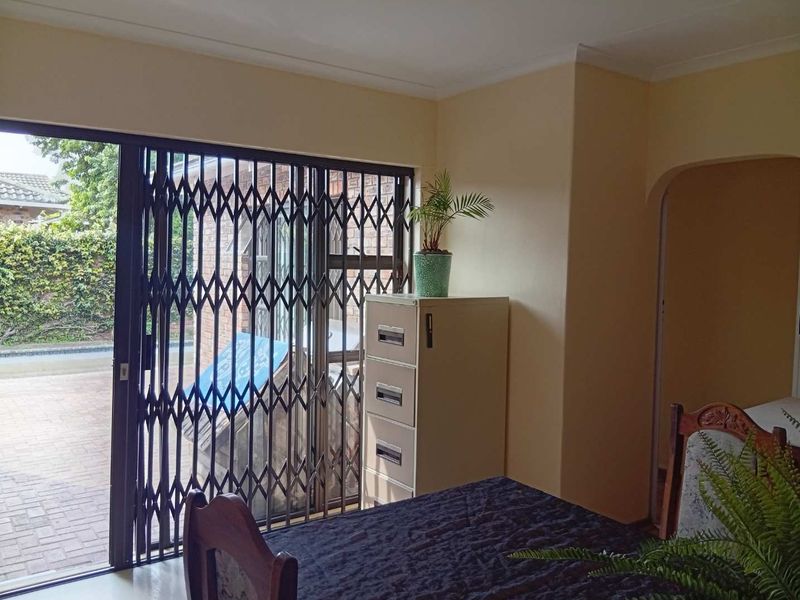 Living area featuring a sliding glass door with a security gate, providing access to the exterior and an arched entryway to adjacent rooms.