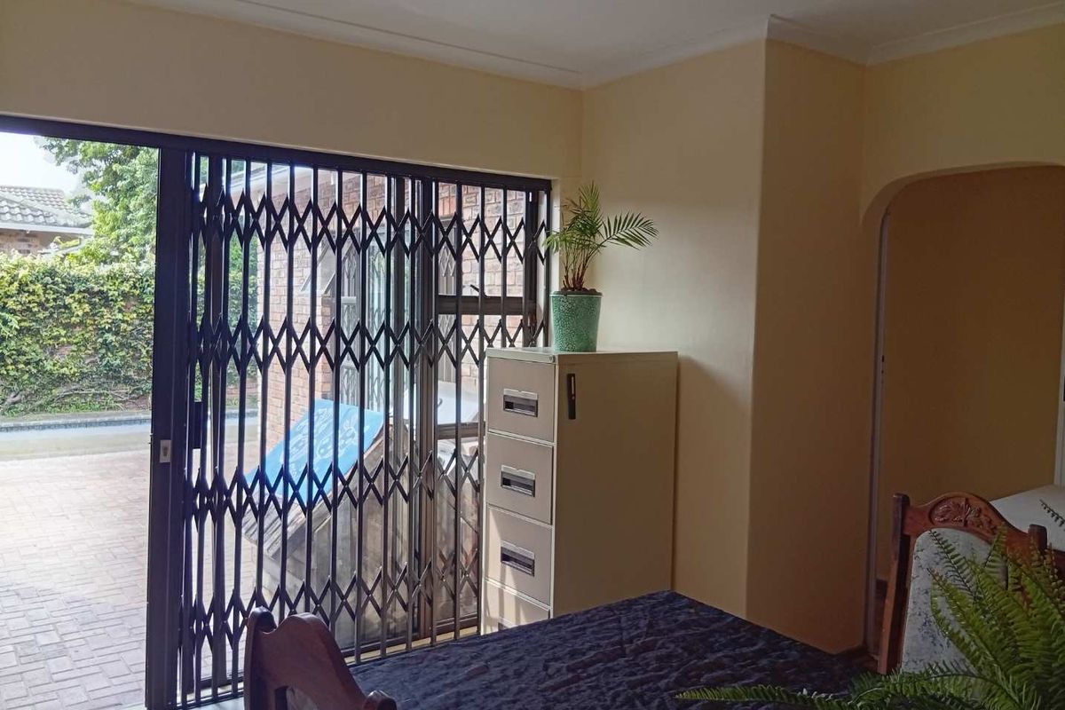 Living area featuring a sliding glass door with a security gate, providing access to the exterior and an arched entryway to adjacent rooms.