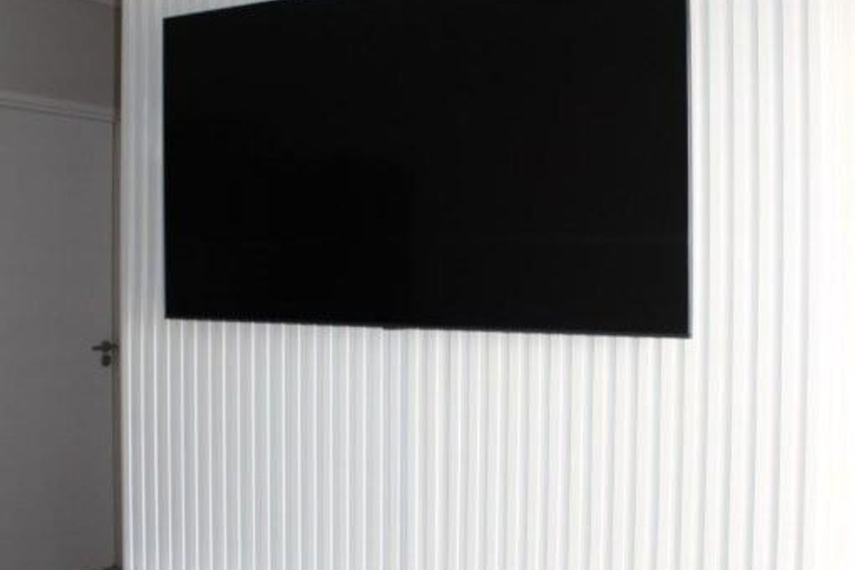 A modern living room feature wall with vertical slat paneling, a wall-mounted television, and a sleek, white floating media console.