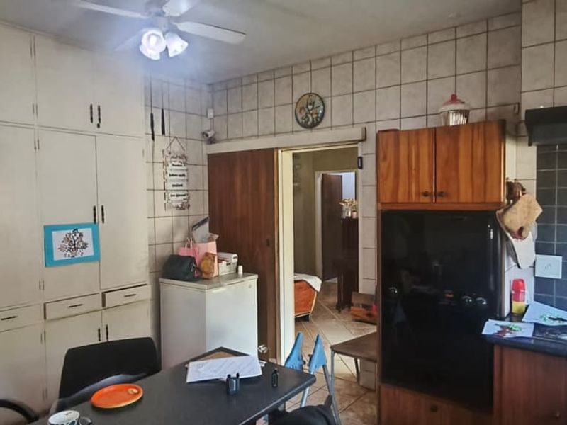 A dated kitchen featuring extensive built-in cabinetry, tiled wall finishes, and a built-in oven with an extractor fan.