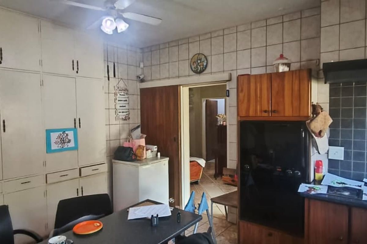 A dated kitchen featuring extensive built-in cabinetry, tiled wall finishes, and a built-in oven with an extractor fan.