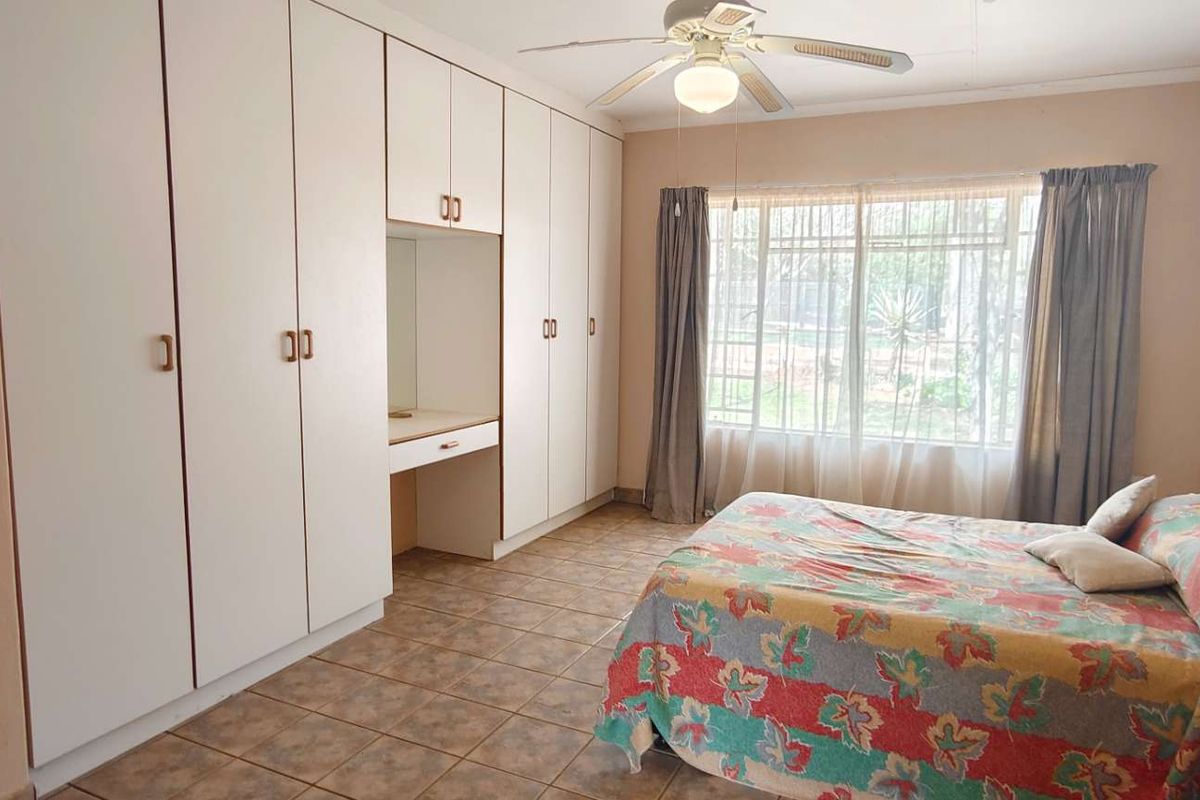 A bedroom featuring extensive built-in cabinetry with an integrated vanity desk, tiled flooring, and a ceiling fan.