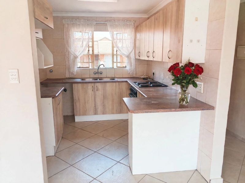 A functional kitchen featuring laminate cabinetry, tiled splashbacks, a double basin sink, and built-in cooking appliances, offering a practical layout for daily use.