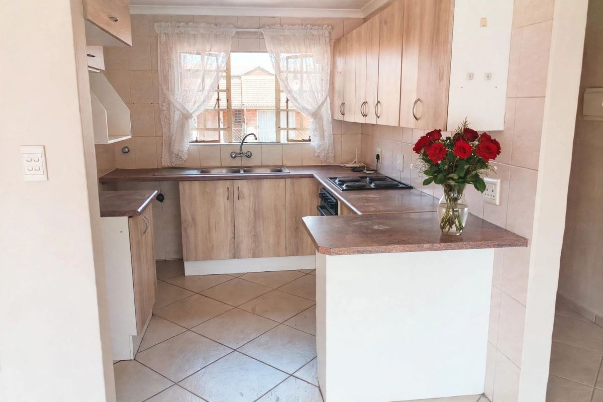 A functional kitchen featuring laminate cabinetry, tiled splashbacks, a double basin sink, and built-in cooking appliances, offering a practical layout for daily use.
