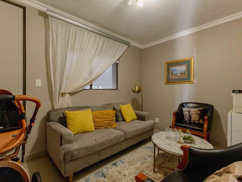 A cozy living room featuring neutral wall tones, crown molding, and tiled flooring, providing a comfortable and functional space for relaxation.