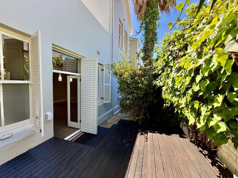 A private outdoor timber deck area featuring french doors with louvre shutters, providing a seamless transition between indoor and outdoor living spaces.