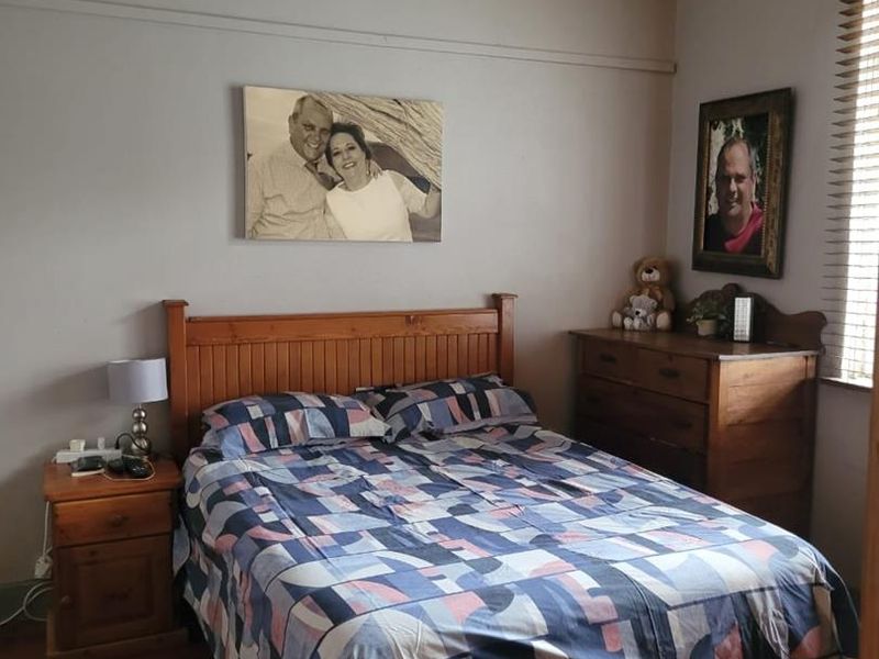 A cozy bedroom featuring classic picture rails, decorative cornice detailing, hardwood flooring, and timber window blinds.