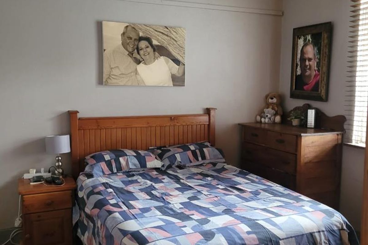 A cozy bedroom featuring classic picture rails, decorative cornice detailing, hardwood flooring, and timber window blinds.