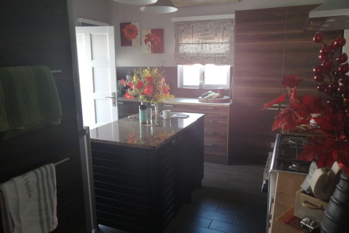 A functional kitchen featuring dark wood cabinetry, a central island with a stone countertop, and tiled flooring.
