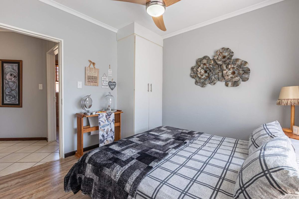 A well-maintained bedroom featuring built-in cupboards, a ceiling fan, and neutral wall finishes, providing a comfortable and functional living space.