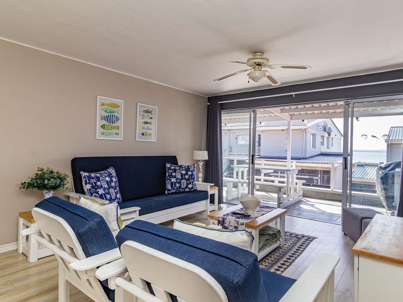 A bright living room featuring laminate flooring, a ceiling fan, and large sliding glass doors that provide access to an outdoor patio area.