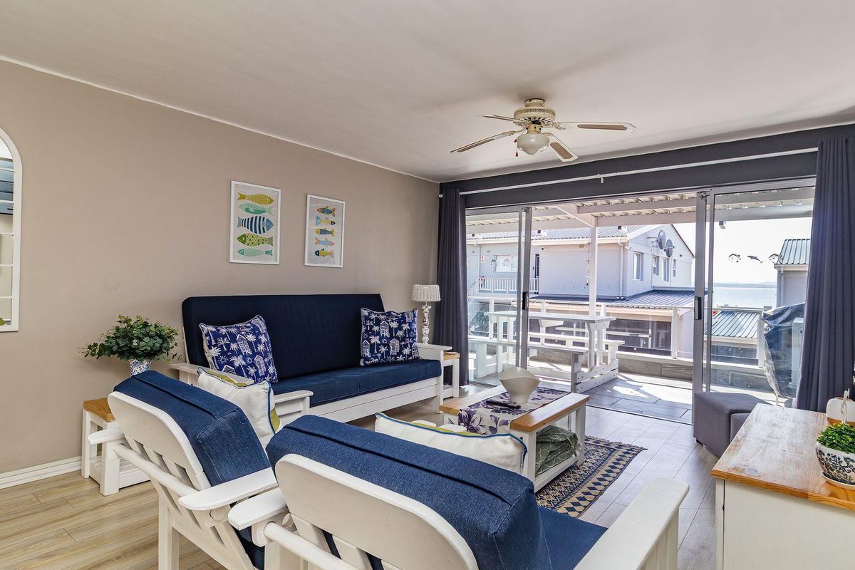 A bright living room featuring laminate flooring, a ceiling fan, and large sliding glass doors that provide access to an outdoor patio area.