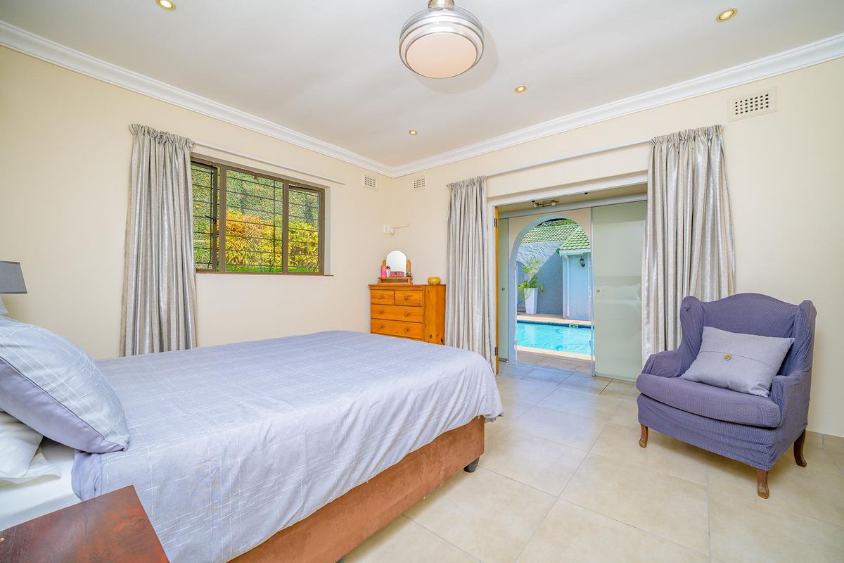 Spacious bedroom featuring tiled flooring, recessed lighting, and a sliding glass door providing direct access to the outdoor pool area.