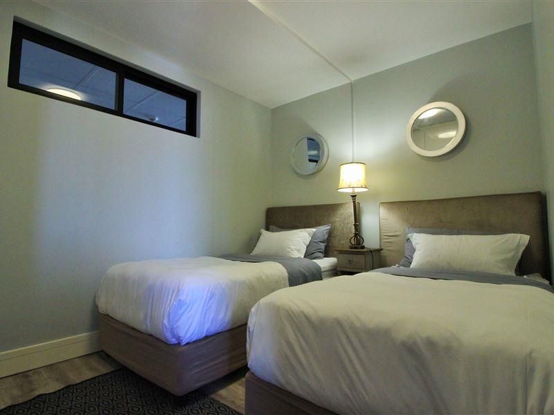 A compact bedroom featuring a high-level clerestory window, neutral wall finishes, and modern flooring.
