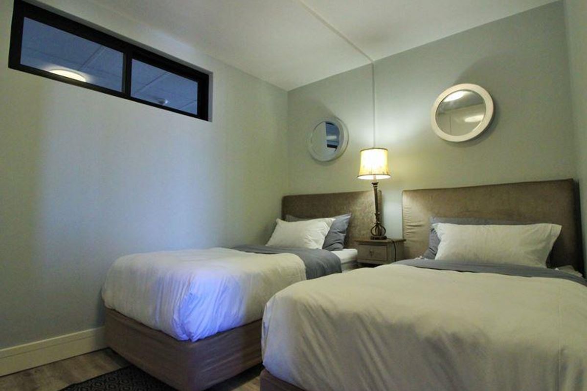 A compact bedroom featuring a high-level clerestory window, neutral wall finishes, and modern flooring.