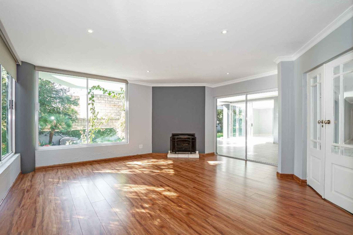 Spacious living room featuring wood-look laminate flooring, a built-in fireplace, large windows, and sliding glass doors leading to an outdoor patio area.