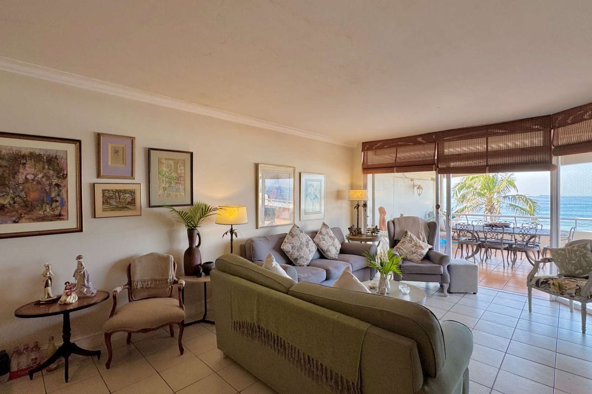 Spacious living room featuring tiled flooring and large sliding glass doors that open onto a balcony with ocean views.