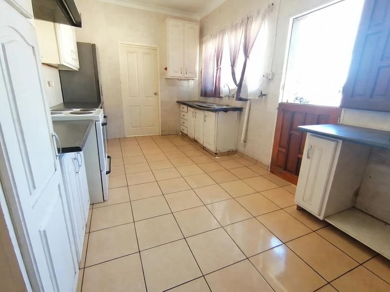 A functional kitchen featuring tiled flooring, built-in cabinetry, and a double sink, offering a practical layout with potential for cosmetic updates.