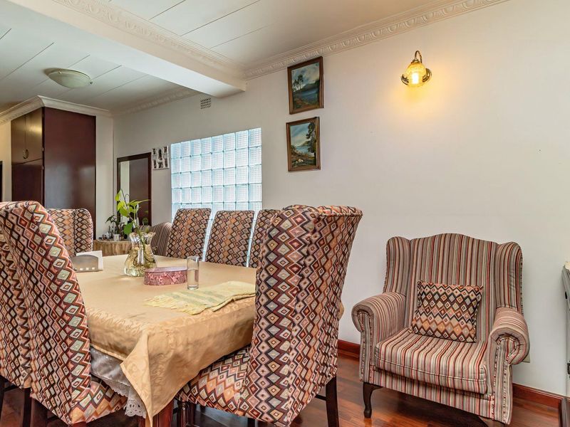 A dining room featuring laminate flooring, decorative crown molding, and a distinctive glass block window providing natural light.