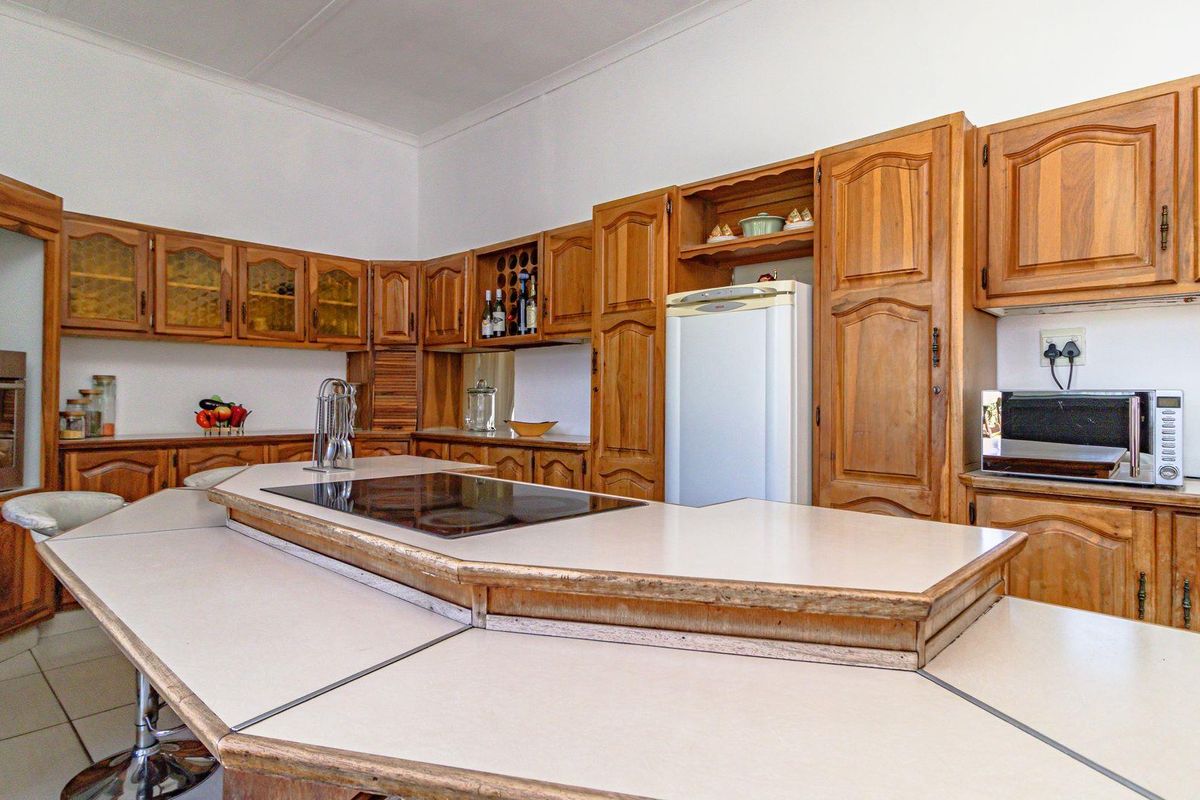 A spacious kitchen featuring extensive timber cabinetry, a large central island with a built-in hob, and integrated oven.