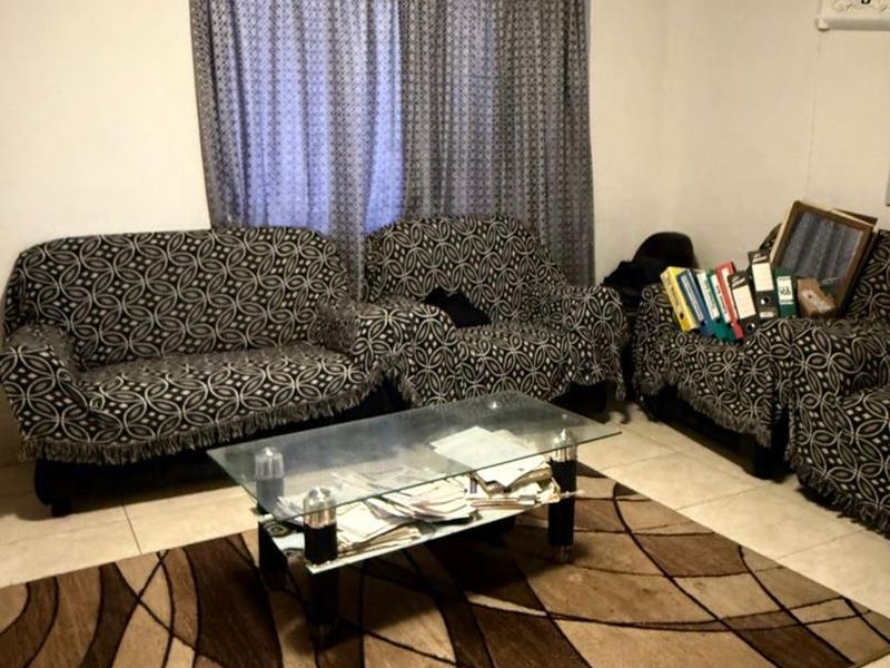 A living room area featuring tiled flooring and a curtain rod, providing a functional space for relaxation.