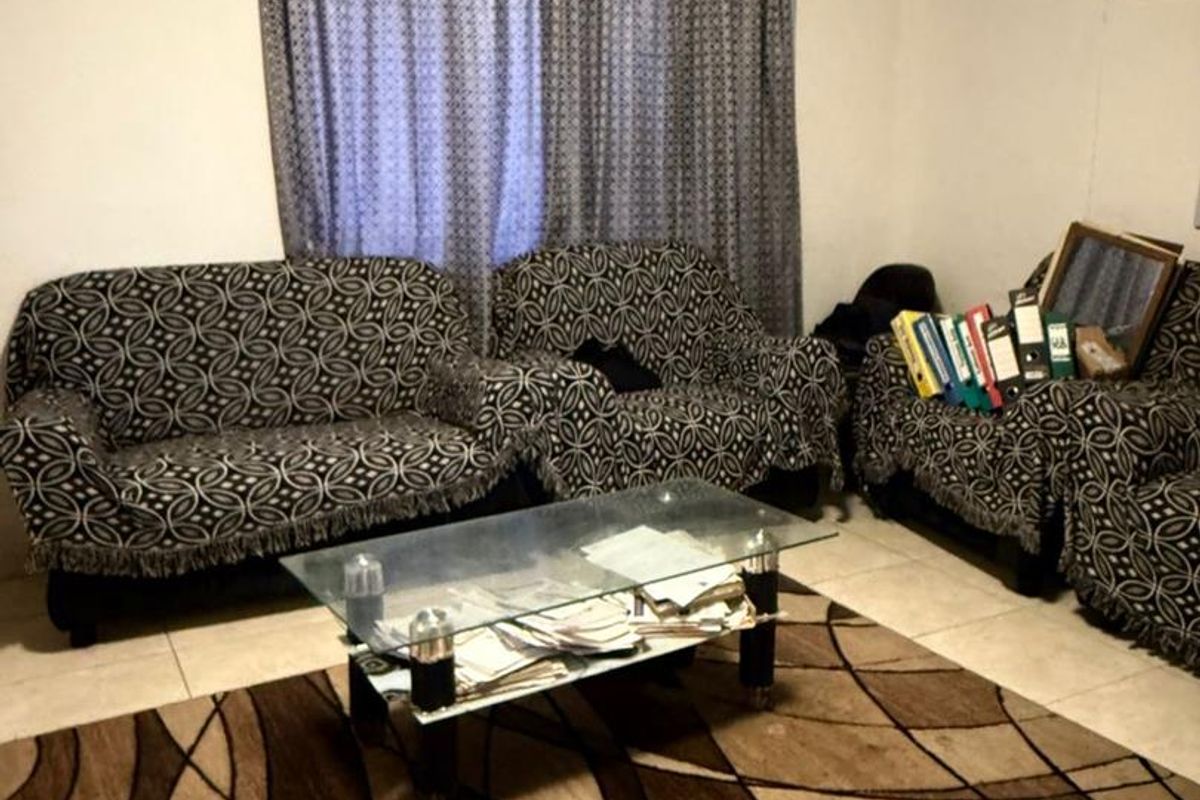 A living room area featuring tiled flooring and a curtain rod, providing a functional space for relaxation.