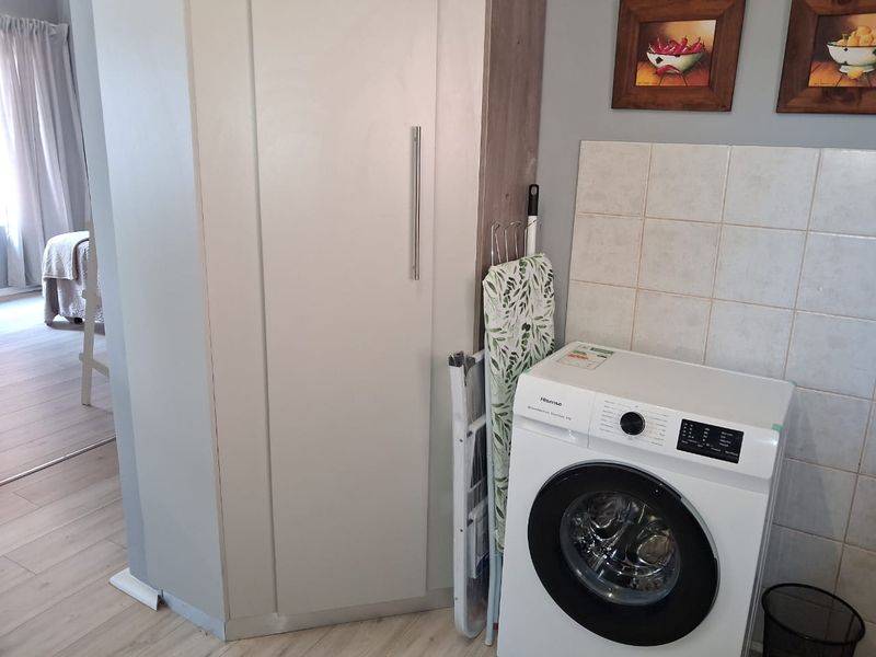 A functional laundry area featuring built-in cabinetry and tiled splashback, providing practical utility space for household tasks.