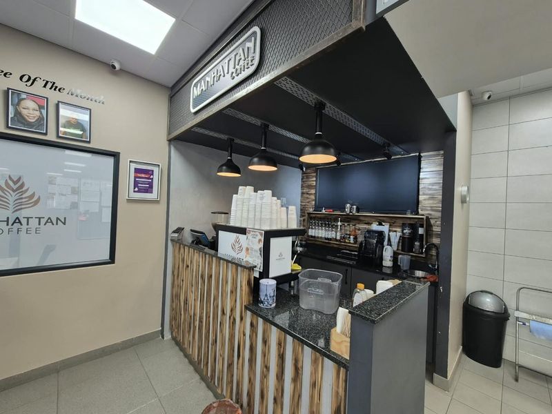 A compact commercial coffee service station featuring a granite countertop, pendant lighting, and a dedicated prep area with integrated sink and cabinetry.