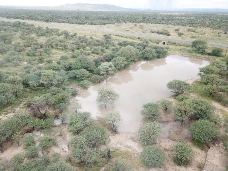 Aerial view of the small holding property featuring a natural dam and surrounding bushveld landscape with road access.
