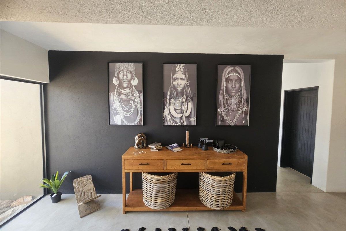 A modern interior space featuring a striking black accent wall, polished concrete flooring, and large glass sliding doors providing natural light.