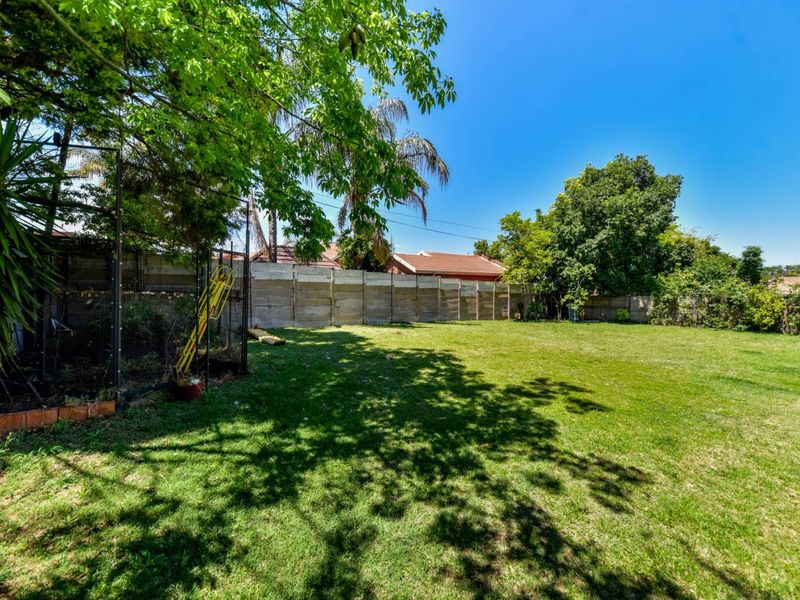 A spacious, level backyard featuring a well-established lawn, mature trees, and timber boundary fencing, offering a private outdoor space.