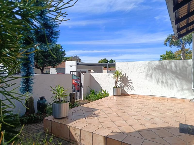 A clean, tiled outdoor patio area featuring a boundary wall and metal gate access, providing a private entrance space for the townhouse.