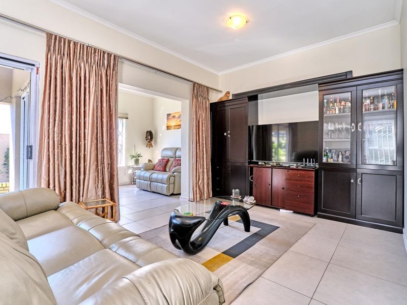 Spacious living room featuring built-in dark wood cabinetry, tiled flooring, and a sliding glass door providing access to the outdoor area.