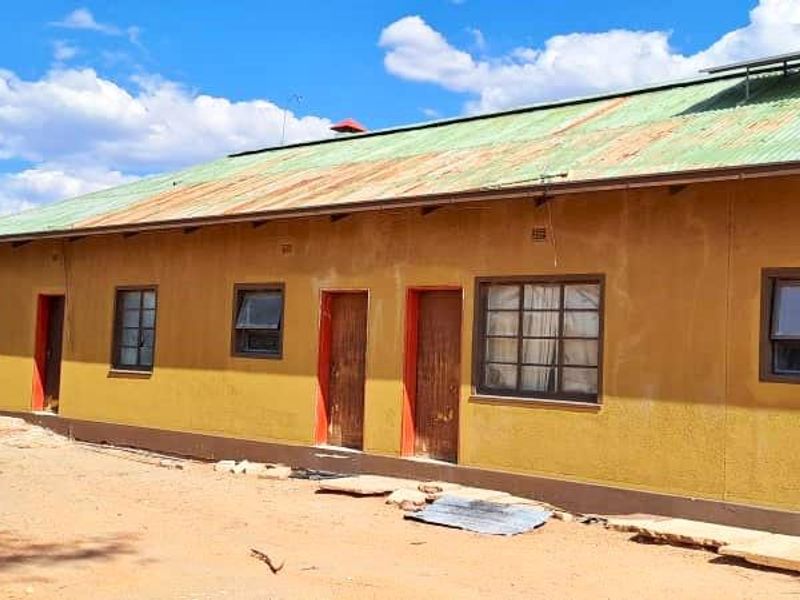 Rear view of a farm building featuring a corrugated metal roof with solar panels, multiple access doors, and steel-framed windows.