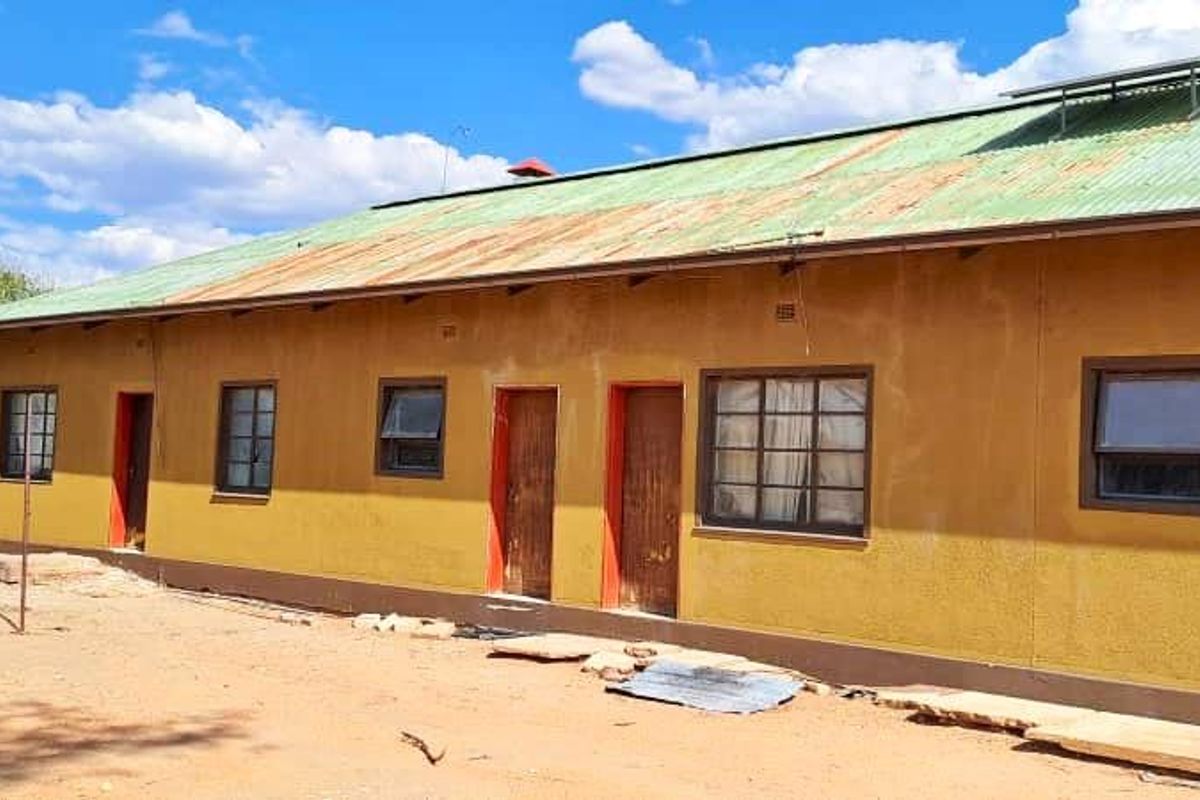 Rear view of a farm building featuring a corrugated metal roof with solar panels, multiple access doors, and steel-framed windows.