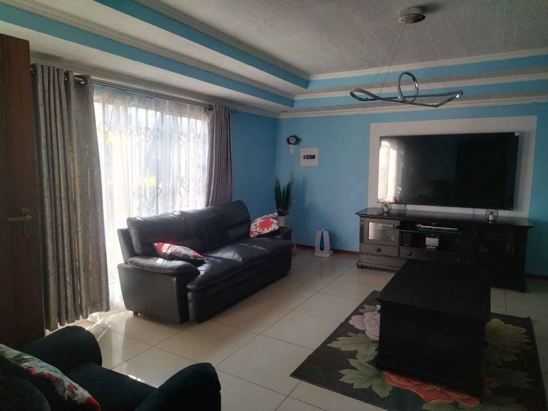 A living room featuring tiled flooring, a recessed ceiling design, and a sliding glass door providing natural light.